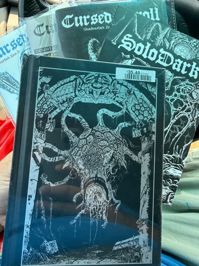 Shrink-wrapped Shadowdark, Solo Dark, and Cursed Scrolls volumes 1–3 laid out on a game store table